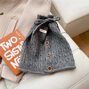 Detail of dark grey cable knit neck warmer featuring rustic wood buttons and drawstring