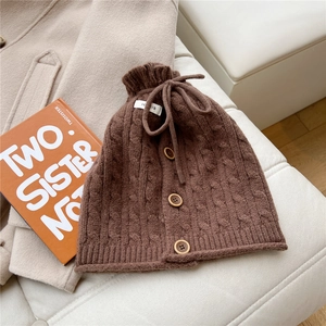 Detail of chunky knit texture with drawstring bow and wooden buttons on brown snood
