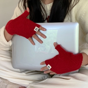 Détail de gants tricotés rouges sans doigts avec étiquette logo utilisés avec un ordinateur
