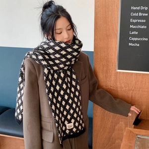 Détail de l'écharpe en tricot à carreaux noirs et marrons avec étiquette et bordure