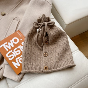 Detail of brown cable knit neck warmer with wooden buttons and adjustable drawstring