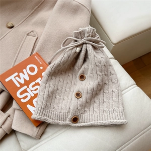 Detailed cable knit pattern on beige neck warmer with decorative wooden buttons