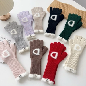 Détail de gants d'hiver tricotés colorés avec poignets en peluche et applique lettre D