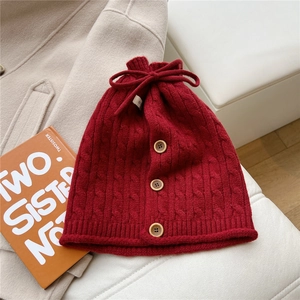 Close-up of deep red cable knit snood with wooden buttons and drawstring bow