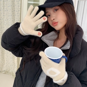 Détail de gants en tricot crème avec broderie cœur et ouvertures pour écran tactile