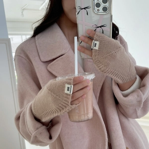 Détail de mitaines en maille rose avec étiquette de marque portées avec un smartphone
