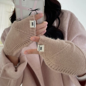 Détail des mitaines en tricot kaki avec texture côtelée et étiquette décorative latérale
