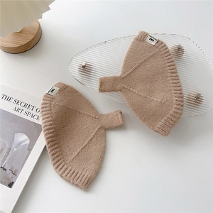 Détail de mitaines en maille beige côtelée avec une étiquette de marque tissée