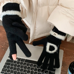 Détail de gants en tricot noirs avec bordure en fourrure blanche et broderie lettre D