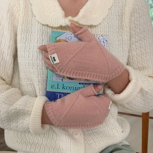 Détail du gant rose en tricot sans doigts avec motif torsadé et étiquette logo