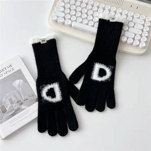 Détail d'un gant en tricot noir avec bordure en fausse fourrure et patch lettre D