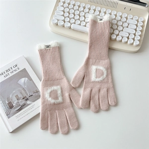 Détail du gant tricoté rose avec lettre D en peluche blanche et bordure en fourrure