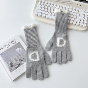 Détail de gants en tricot gris clair avec bordure en fourrure blanche et lettre D