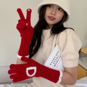 Détail de gants en tricot rouges avec bordure en peluche blanche et broderie lettre D