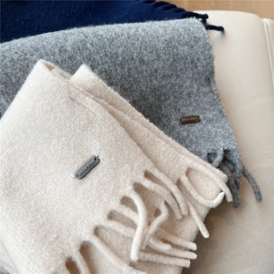 Gros plan d'écharpes en tricot avec franges et étiquette métallique en laine douce