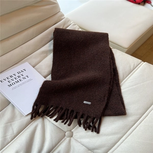 Détails de texture de l'écharpe en tricot marron foncé avec franges et logo en métal
