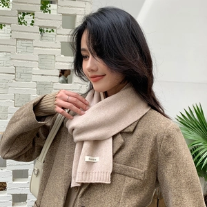 Detail of soft beige knit scarf with Cashmere label paired with a tweed blazer