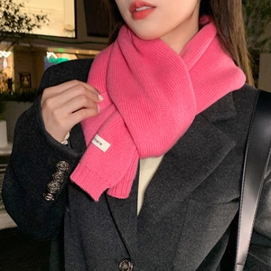 Detailed close-up of rose pink ribbed knit scarf with a white cashmere woven label