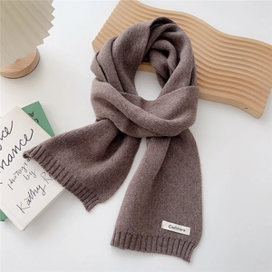 Detail of grey-purple knit scarf showing cashmere label and fine ribbed texture
