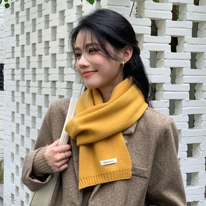 Detail of warm yellow cashmere scarf with ribbed edges styled with a brown blazer
