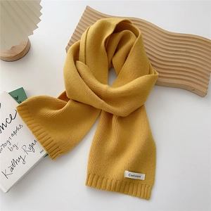 Macro detail of ginger yellow cashmere knit scarf with textured ribbed edges and soft finish