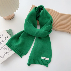 Close-up of bright green knitted scarf with white Cashmere label on a white background