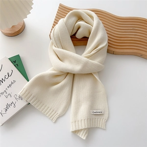 Detail of soft cream knitted scarf featuring cashmere label and ribbed texture edges
