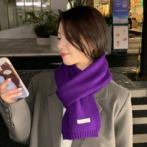 Detailed texture of purple knit scarf with Cashmere label against a grey blazer jacket