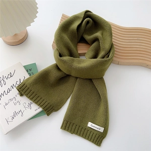 Detailed texture of moss green knitted scarf featuring a white cashmere logo tag
