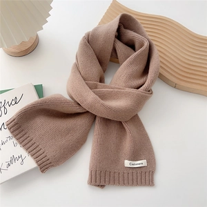 Close-up of brown knit scarf with Cashmere label on minimalist decorative background