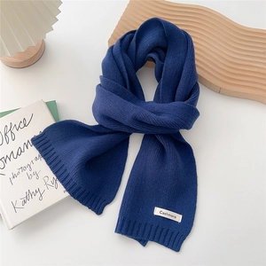Detail of navy cashmere knit scarf with brand label on minimalist aesthetic background