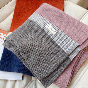 Detailed view of color-block knit scarf showing soft pink and grey ribbed texture