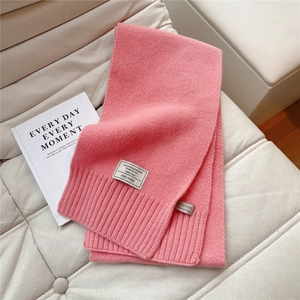 Detail eines rosa gestrickten Wollschals mit 100% Wollsiegel und Rippenstruktur