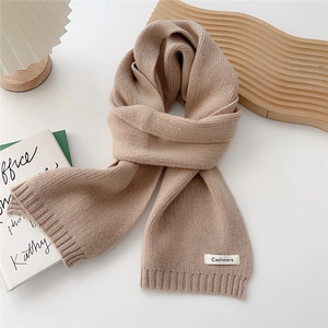 Detail of light beige knitted scarf with fine ribbed texture and Cashmere label