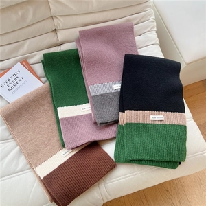Close-up of multi-color chunky knit scarves with soft texture and white woven labels