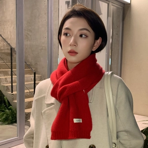 Close-up of red thick knit cashmere scarf texture with white label on white coat