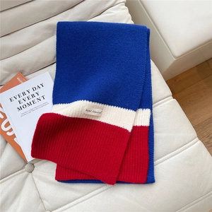 Detail of tricolor knitted scarf featuring ribbed texture and brand woven label