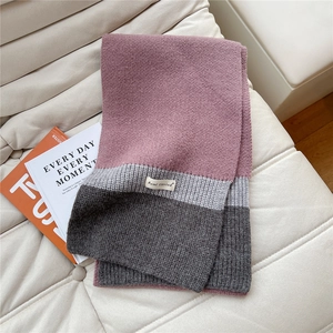 Close-up of three-color knit scarf in pink and grey tones on a beige sofa