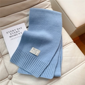 Detailansicht eines blaue Wollschals aus 100% Wolle mit Rippenstrick auf Ledersofa