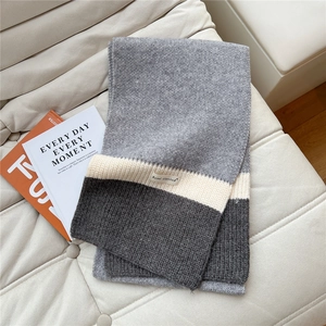 Close-up of tricolor knitted scarf texture with detailed fabric tag and soft weaving