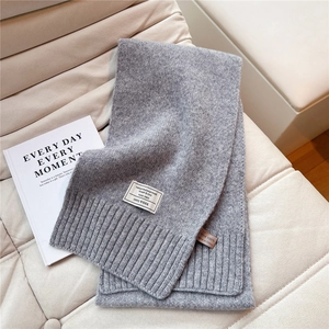 Detailaufnahme des 100% Wolle Etiketts auf dunkelgrauem Strickschal mit Rippmuster
