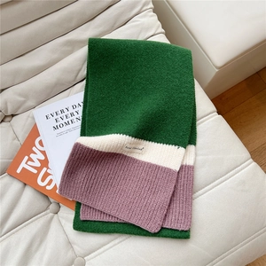 Detail of three-color rib-knit scarf in green and pink with a woven brand label