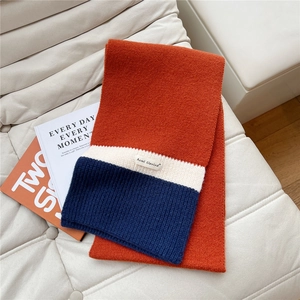 Close-up of soft orange knit scarf showing detailed texture and brand woven label