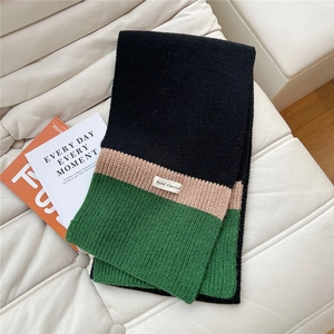 Detailed knit texture of a three-color block scarf in black, beige, and green wool