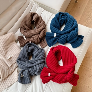 Detail of 100% pure wool scarves with knit texture in various colors on a sofa