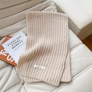 Detail of 100% wool beige ribbed knit scarf with soft texture and premium material label