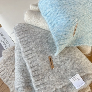 Close-up of soft alpaca blend knit scarves with metal brand logo and cozy texture