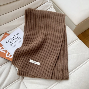 Detailed texture of dark brown knit wool scarf with 100% wool label on sofa