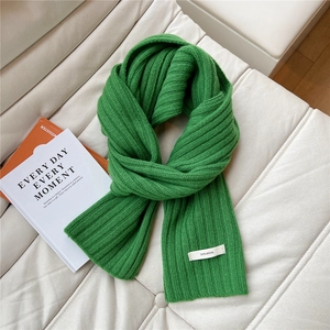 Detail of grass green wool scarf featuring rib knit texture and 100% wool material tag