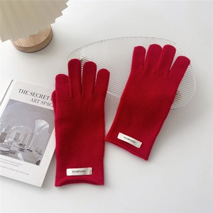 Detail showing 100% wool label on red knitted touchscreen gloves for winter
